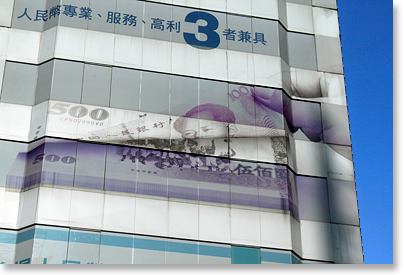 Images of two currency notes, of Taiwan and China, on a skyscraper in Taipei. 