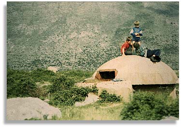On the road to Tirana, Albania. With a mountain in the background children play on top of an abandoned pill-box. Photo by Eloise de Leon.