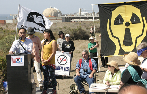 Hirohide Sakuma and Kyoko Sugasawa from the Fukushima region of Japan speak to two hundred protesters in Southern California at the San Onofre Nuclear Generating Station. The March 11, 2011 event was both a commemoration on the one year anniversary of the Fukushima earthquake, tsunami and nuclear power plant disaster which killed close to 16,000 people (with more than 3,000 still missing) and also a call for the decommissioning of the San Onofre plant. Speakers told the protestors that San Onofre, which was currently shut down for repairs, has the worst safety record among U.S. nuclear plants. Photo by Nic Paget-Clarke.